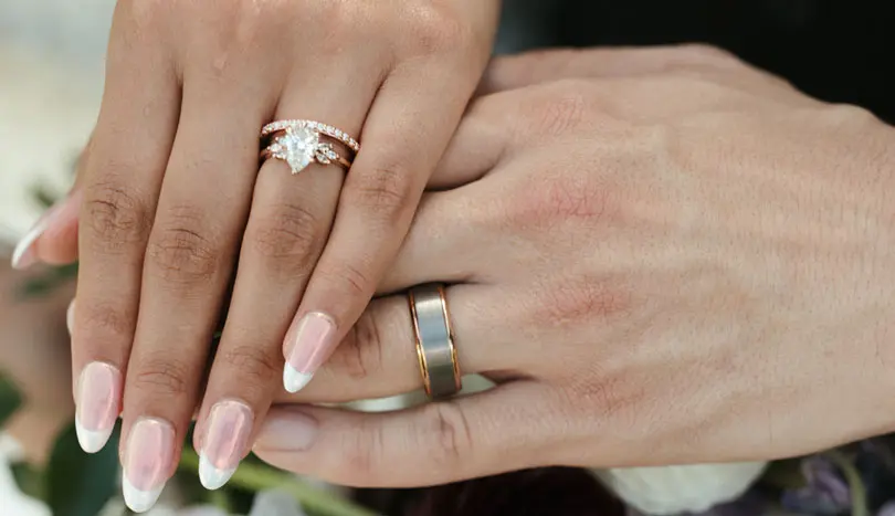 A close up of two hands with wedding rings on