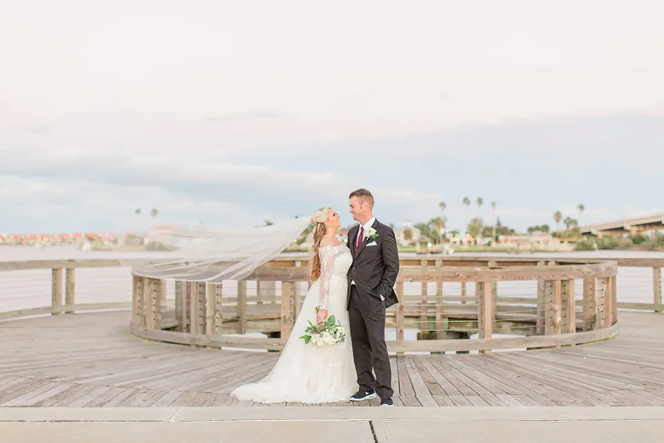 A bride and groom stand on the boardwalk.