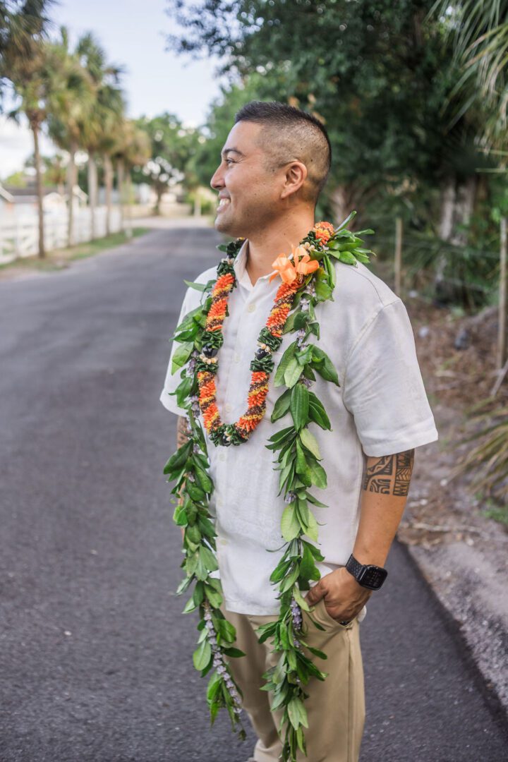 A man with tattoos and a lei on the side of the road.