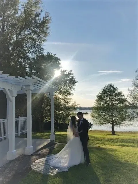 A bride and groom standing in front of the lake.