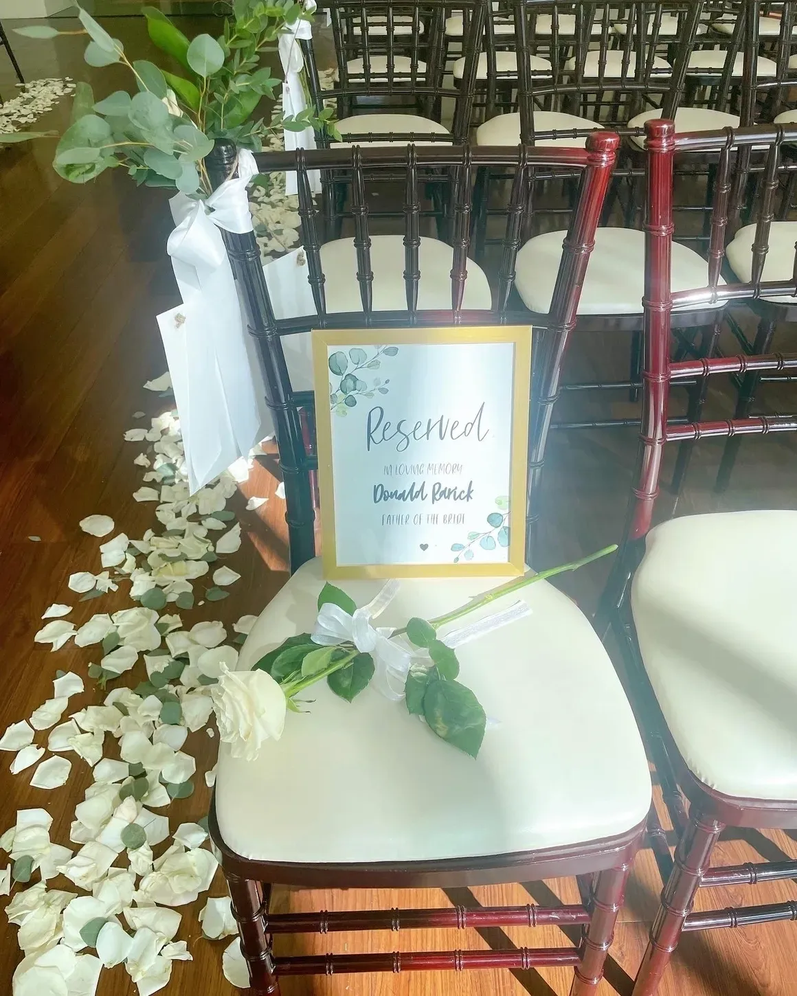 A chair with a sign on it and some flowers