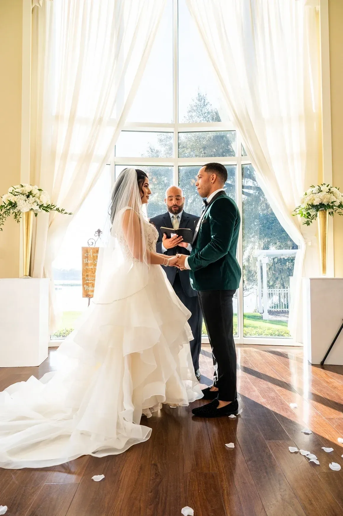 A bride and groom are holding hands while the man is standing next to them.