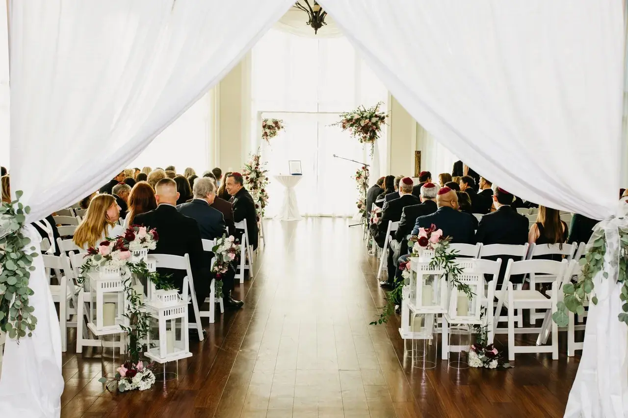A wedding ceremony with many people sitting in chairs.