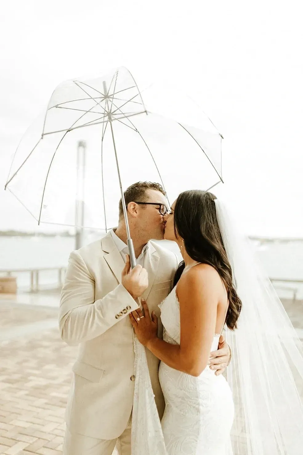 A man and woman kissing under an umbrella.